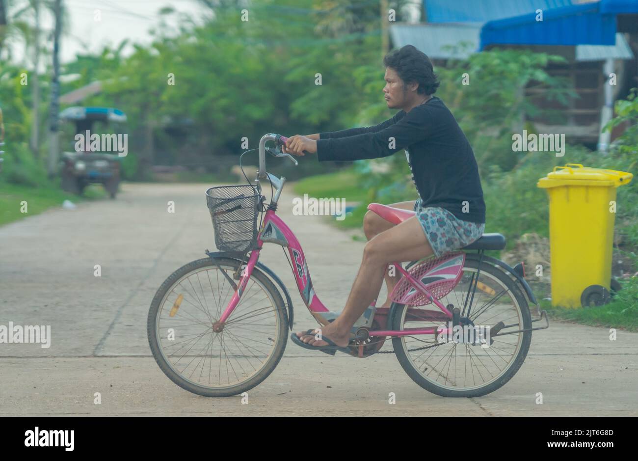 Ein lustiger Moment, als ein Mann auf dem Träger sitzt und auf dem Fahrrad fährt. Stockfoto