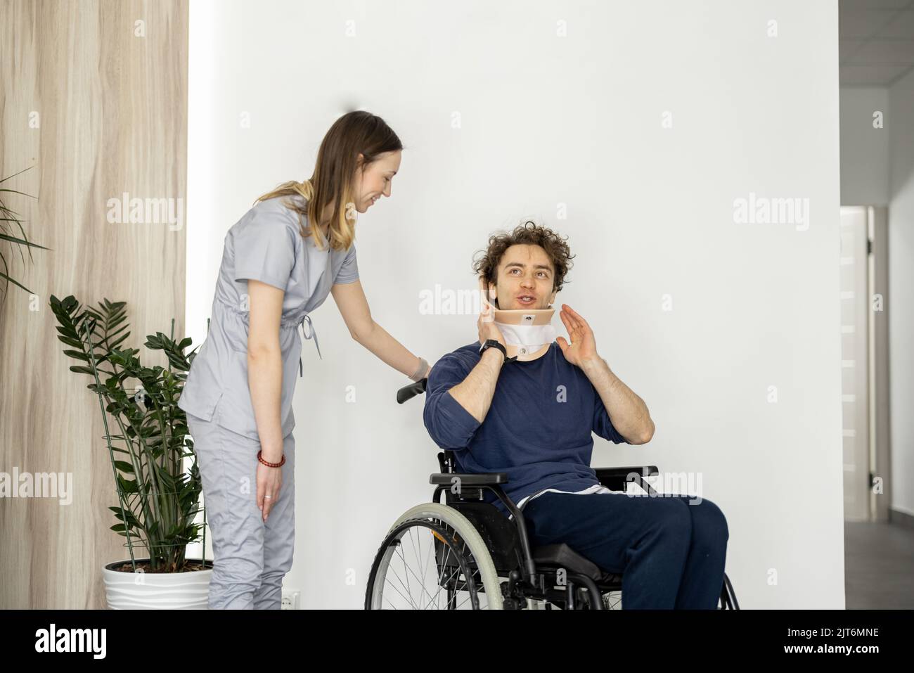 Der Arzt kommuniziert mit einem Mann in einem Rollstuhl mit Nackenverletzung Stockfoto