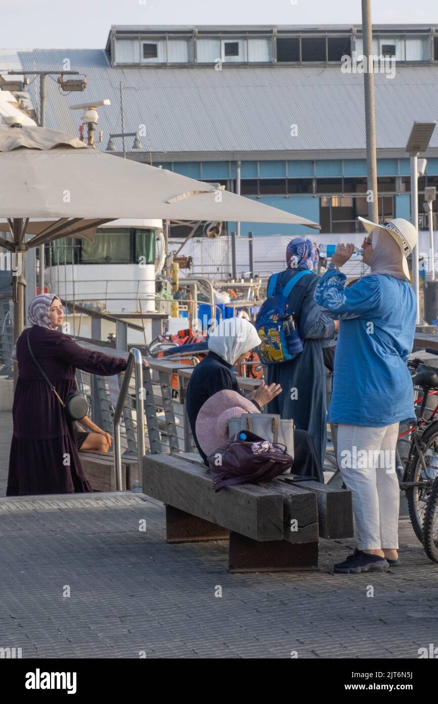 Vier arabische Frauen tragen Hijab-Ruhepausen im Hafen von Jaffa, Israel. Stockfoto