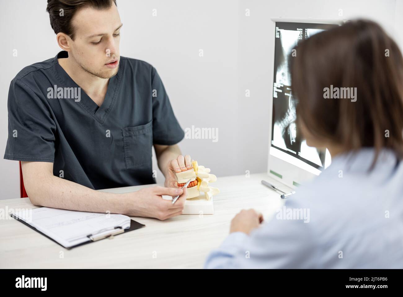 Junge Frau in Absprache mit einem Physiotherapeuten in der Arztpraxis Stockfoto