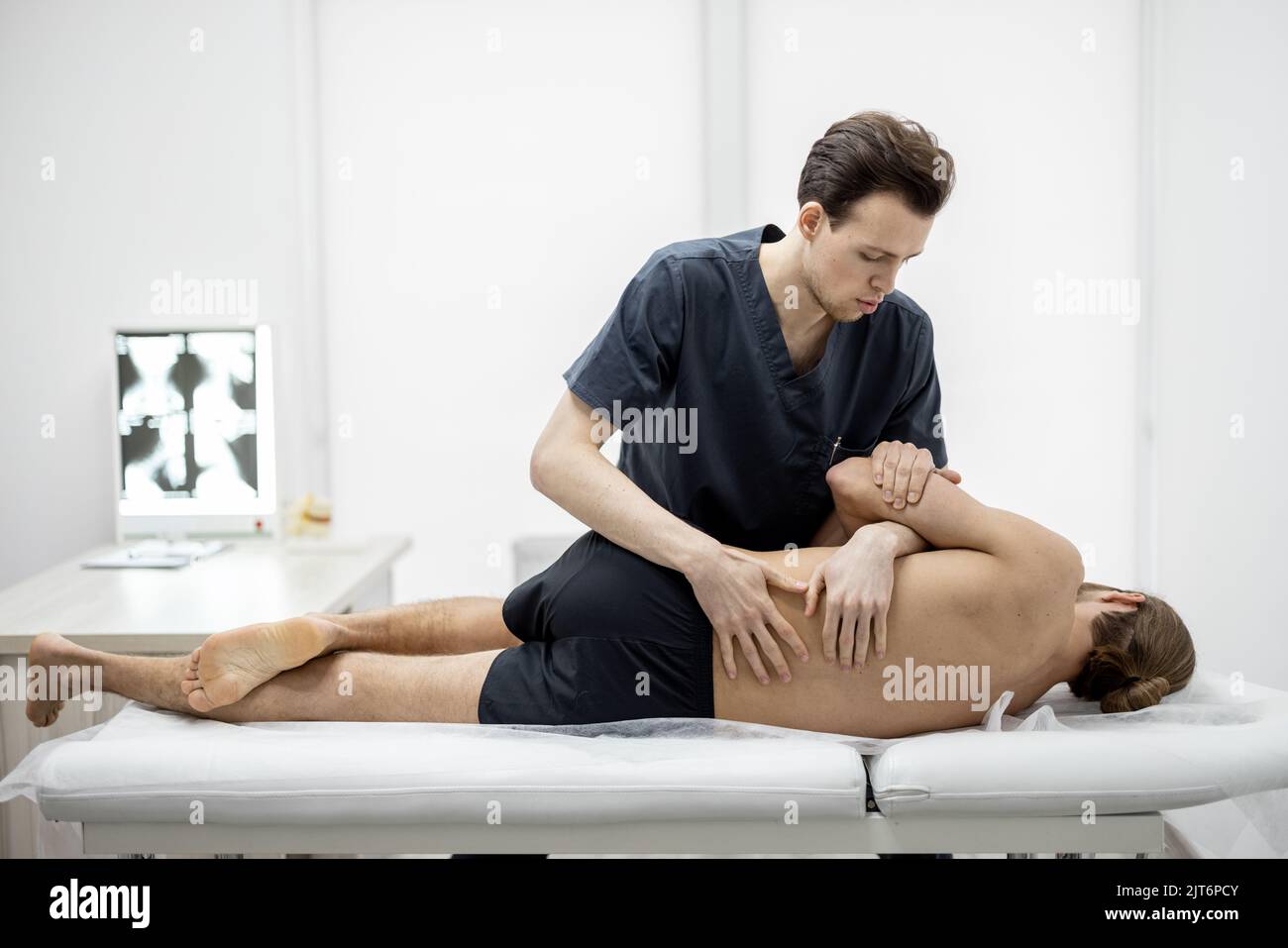 Physiotherapeut führt manuelle Therapie mit einem jungen sportlichen Kerl in der Arztpraxis durch Stockfoto