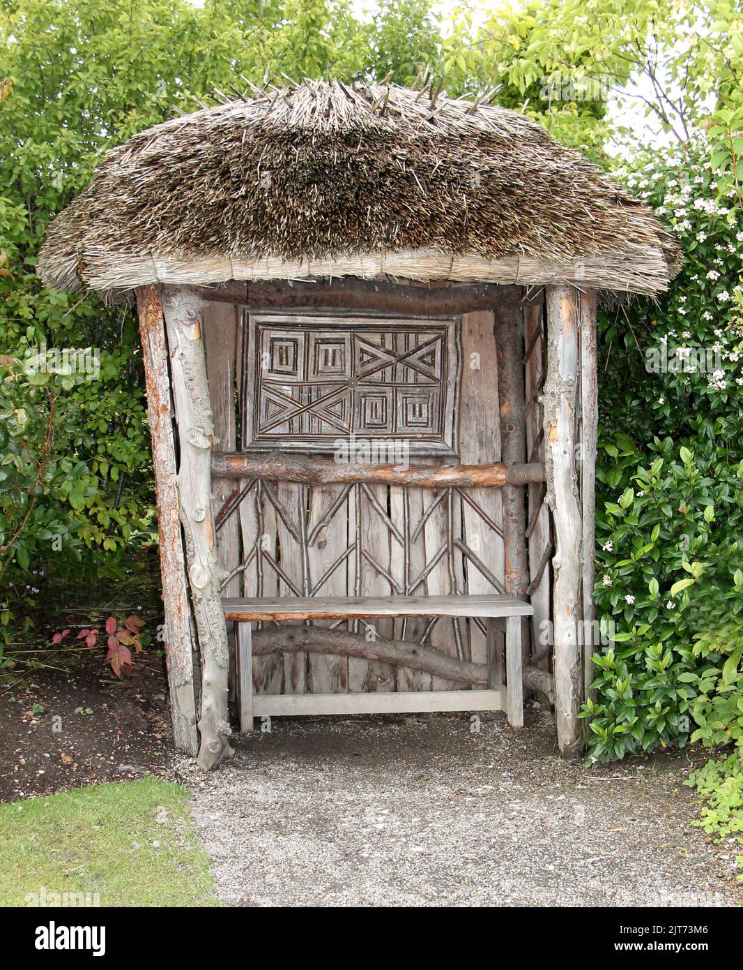 Ein reetgedeckter hölzerner Gartenbank-Sitz. Stockfoto