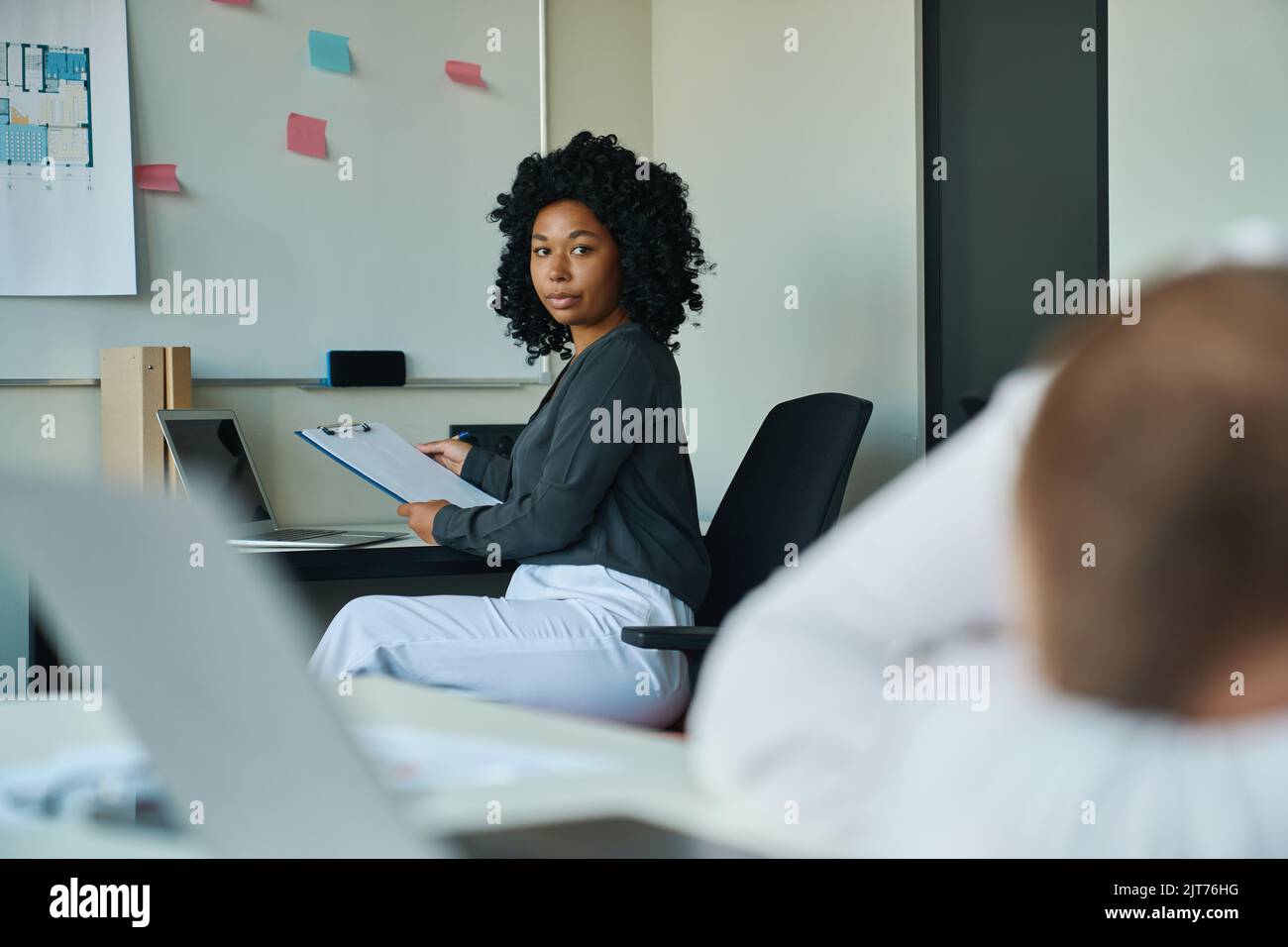 Frau, die einen Kollegen ansieht, der am Tisch eingeschlafen ist Stockfoto