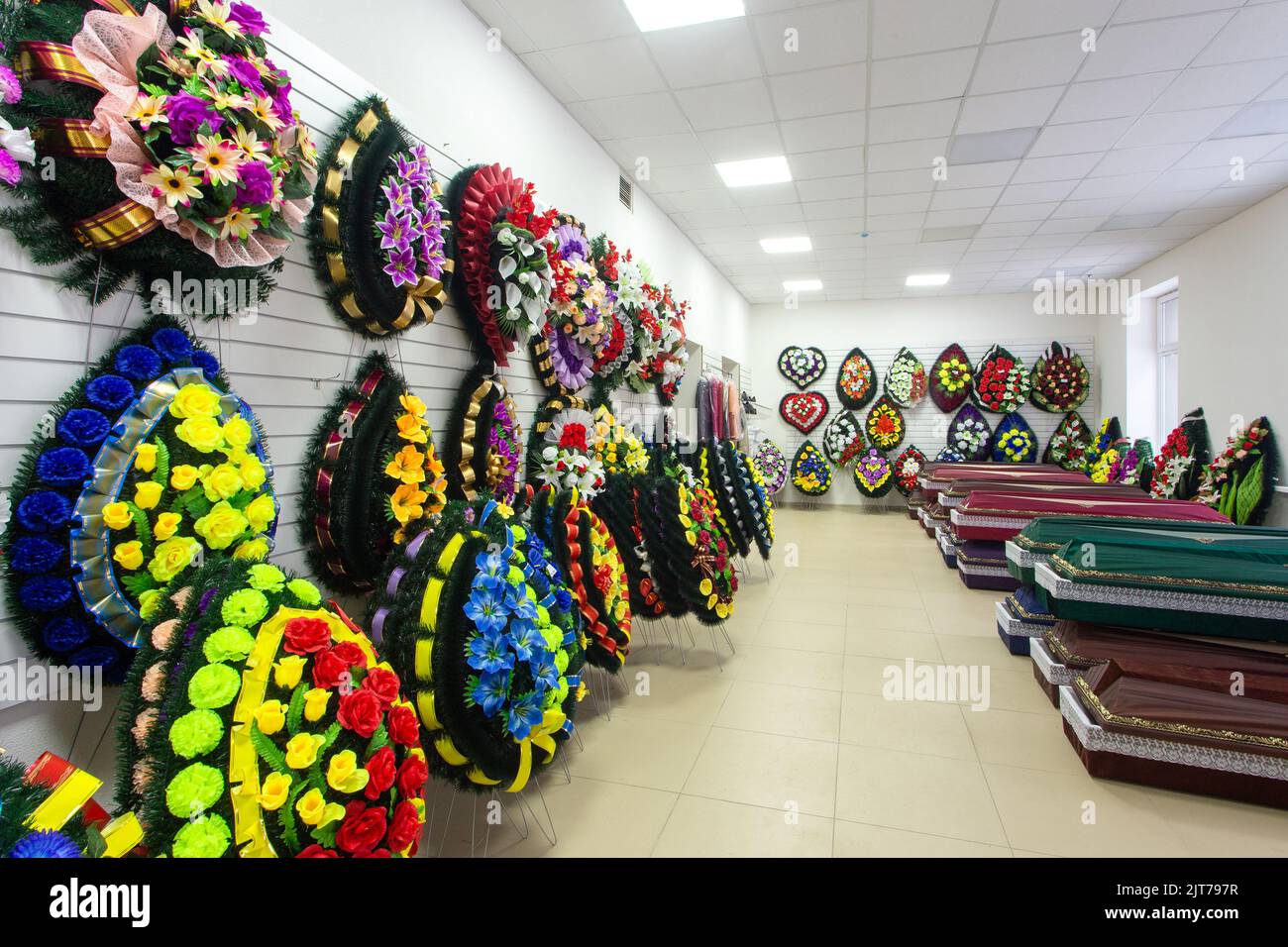 Innenraum des Raumes mit Bestattungszubehör. Geschäft mit Särgen, Beerdigungskränzen und Blumen. Stockfoto