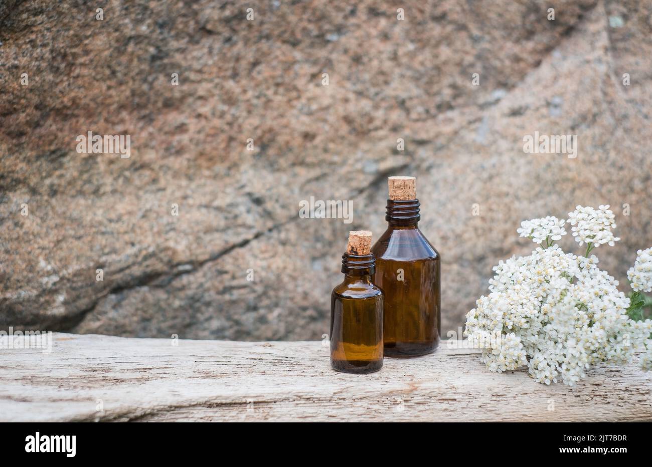 Kleine braune Medizinflasche auf natürlichem Hintergrund mit weißen Schafgarben-Blüten. Stockfoto