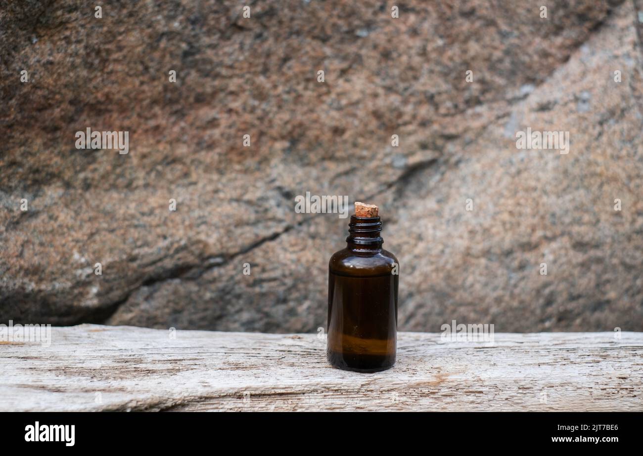 Kleine braune Glasflasche mit Medikamenten auf veraltertem Holzhintergrund. Stockfoto