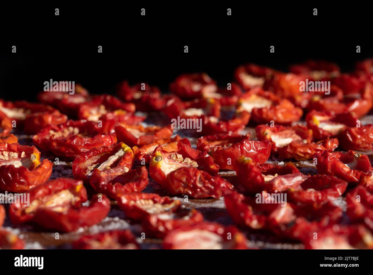 Nahaufnahme und Hintergrund von Tomaten liegen in der Sonne zum Trocknen. Der Hintergrund ist schwarz. Stockfoto