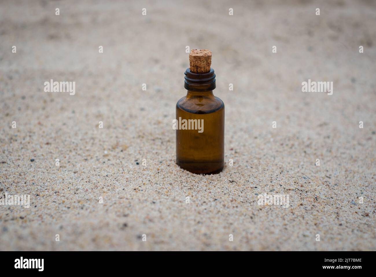 Kleine braune Medizinflasche auf beigem Sandhintergrund. Leerer Kopierbereich. Stockfoto