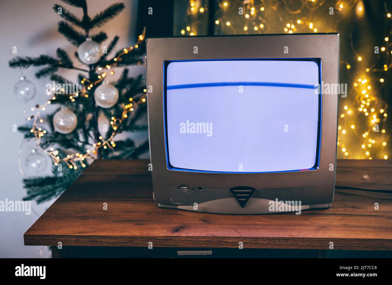 Retro-Fernseher mit Glitch-Effekt in einem Raum mit Weihnachtsdekorationen auf einem Holztisch Stockfoto