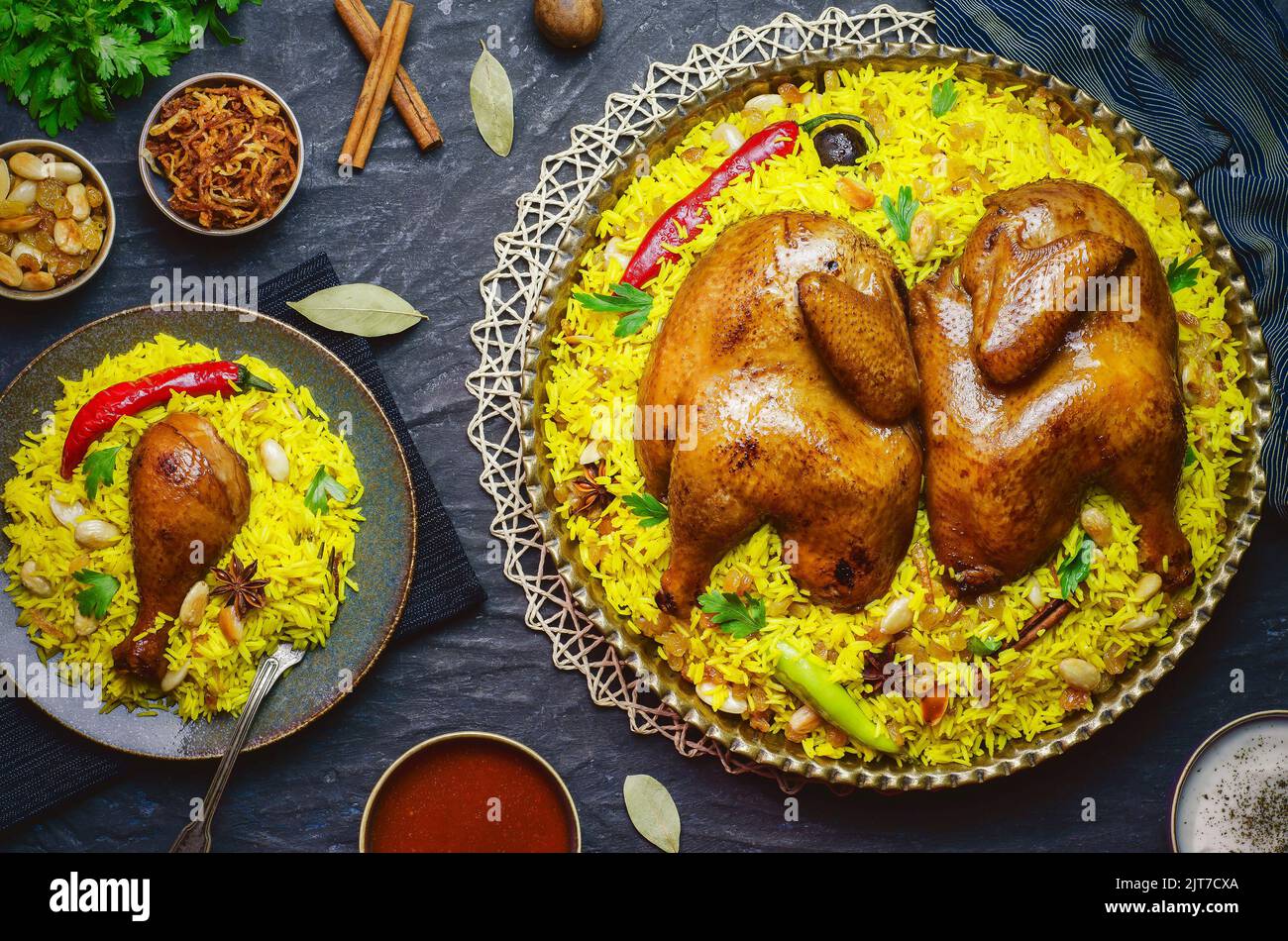 Arabische Küche; Chicken 'Kabsa' oder Chicken Beryani Reis. Serviert mit goldgebratenen Zwiebeln, knusprig gerösteten Nüssen, Rosinen und frischer Petersilie. Stockfoto
