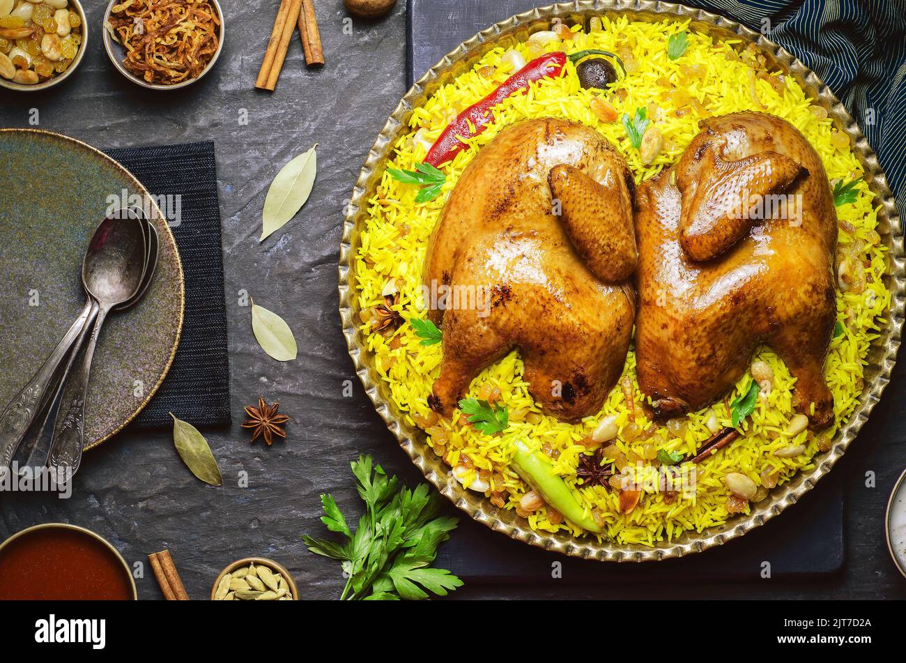 Arabische Küche; Chicken 'Kabsa' oder Chicken Beryani Reis. Serviert mit goldgebratenen Zwiebeln, knusprig gerösteten Nüssen, Rosinen und frischer Petersilie. Stockfoto