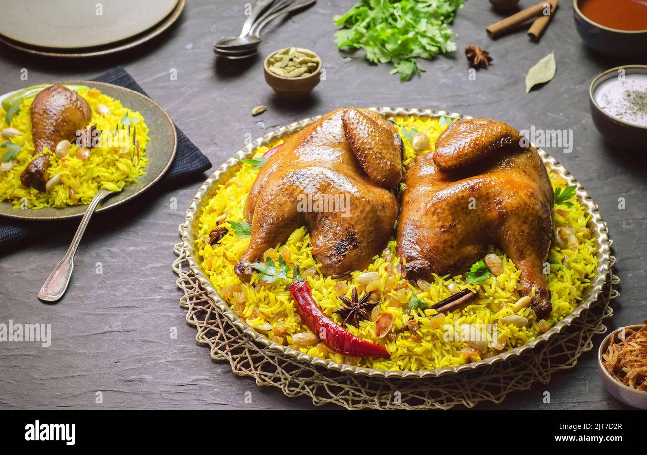 Arabische Küche; Chicken 'Kabsa' oder Chicken Beryani Reis. Serviert mit goldgebratenen Zwiebeln, knusprig gerösteten Nüssen, Rosinen und frischer Petersilie. Stockfoto