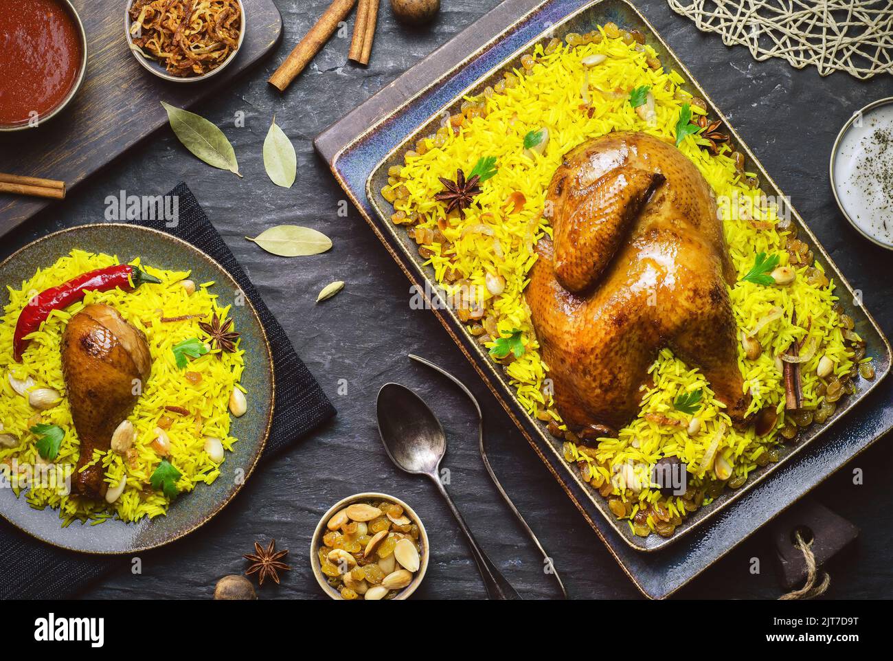 Arabische Küche; Chicken 'Kabsa' oder Chicken Beryani Reis. Serviert mit goldgebratenen Zwiebeln, knusprig gerösteten Nüssen, Rosinen und frischer Petersilie. Stockfoto