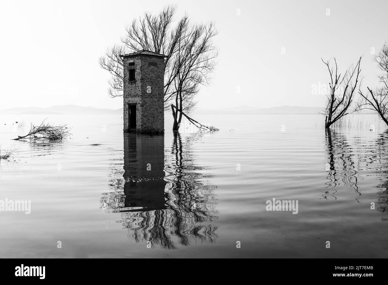 Ein alter Turm und Bäume in der Mitte eines Sees, mit perfekt symmetrischen Reflexionen Stockfoto