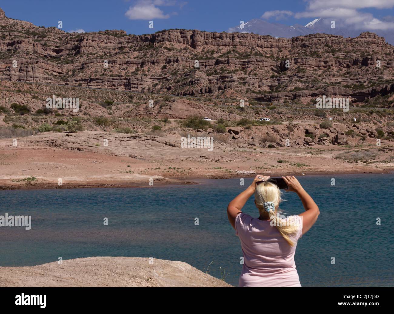 Blonde Frau, die ein Foto in einer wunderschönen Landschaft mit einem See und Bergen. Stockfoto