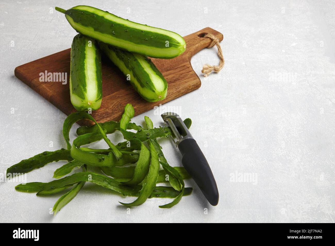 Mit Haut und Messer auf einem braunen Holzschneidebrett auf einem hellgrauen Betontisch Stockfoto