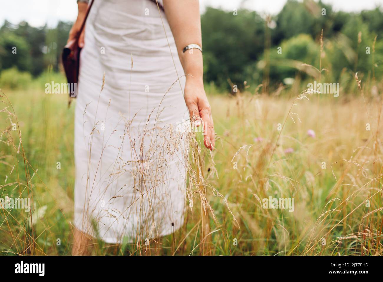 Psychische Gesundheit. Frau, die auf der Wiese geht, fühlt sich in Harmonie mit der Natur und balanciert berührendes Gras. Gesunder Lebensstil Stockfoto