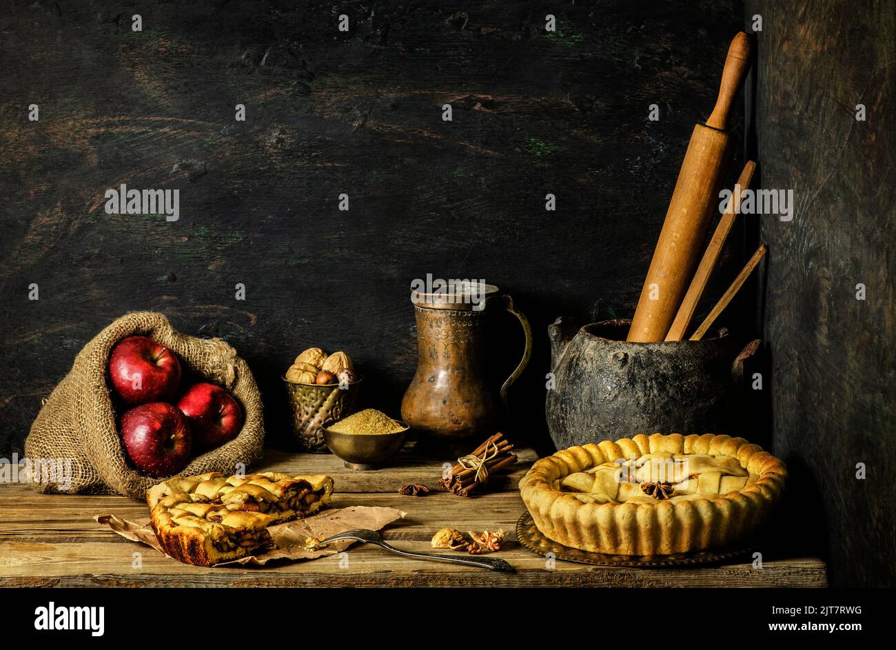 Klassisches Stillleben mit Apfelkuchen mit rotem Apfel und frischen Zutaten auf rustikalem Holzhintergrund. Stockfoto