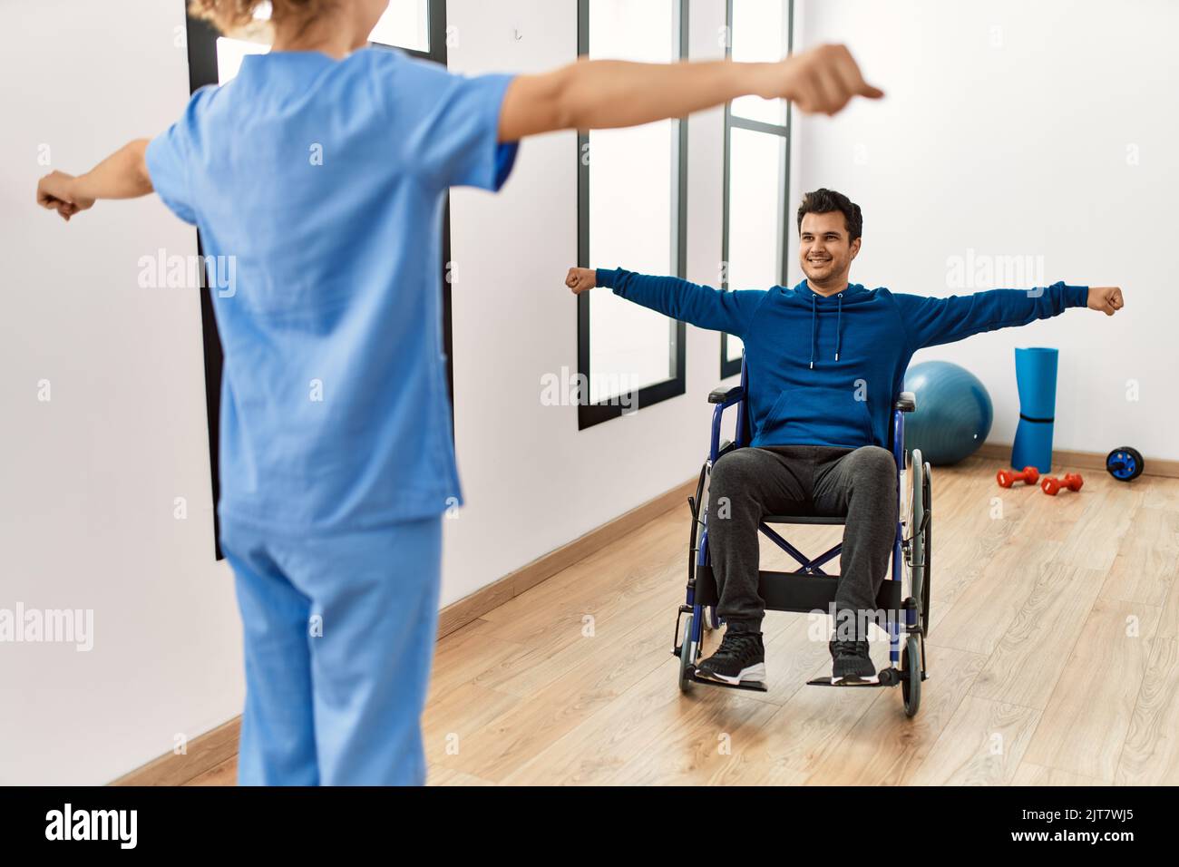 Ein junger behinderter Mann macht BewegungsÜbungen und sitzt auf dem Rollstuhl in der Klinik