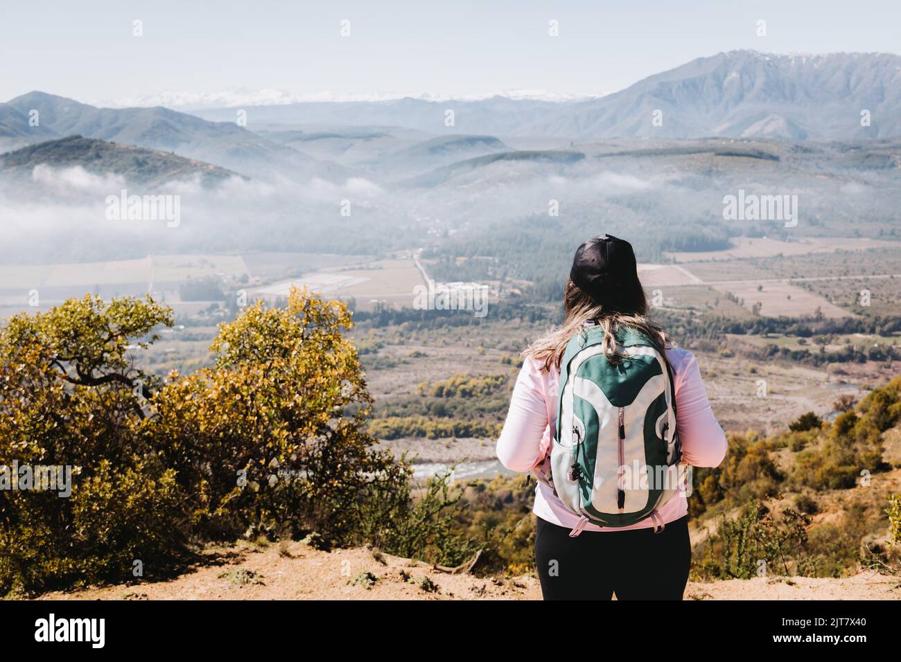 Rückansicht junge latein plus size Frau mit Rucksack auf, Blick von der Spitze eines Hügels betrachten Stockfoto