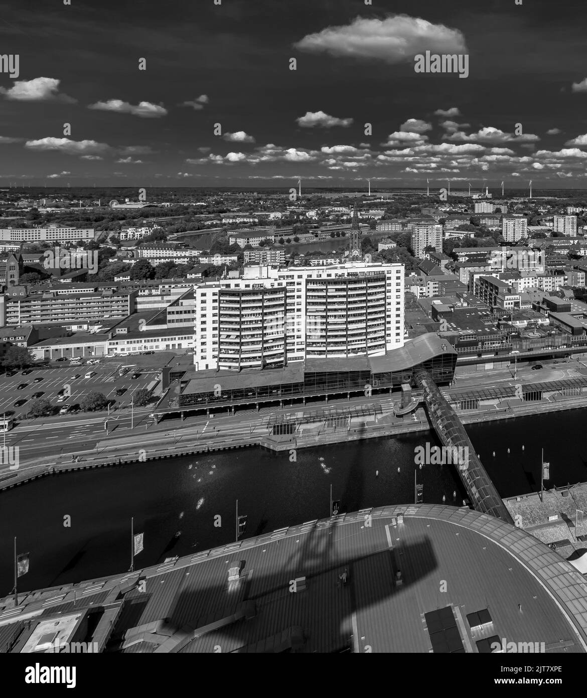 Eine Graustufenaufnahme eines Stadtbildes und eines Flusses unter bewölktem Himmel Stockfoto