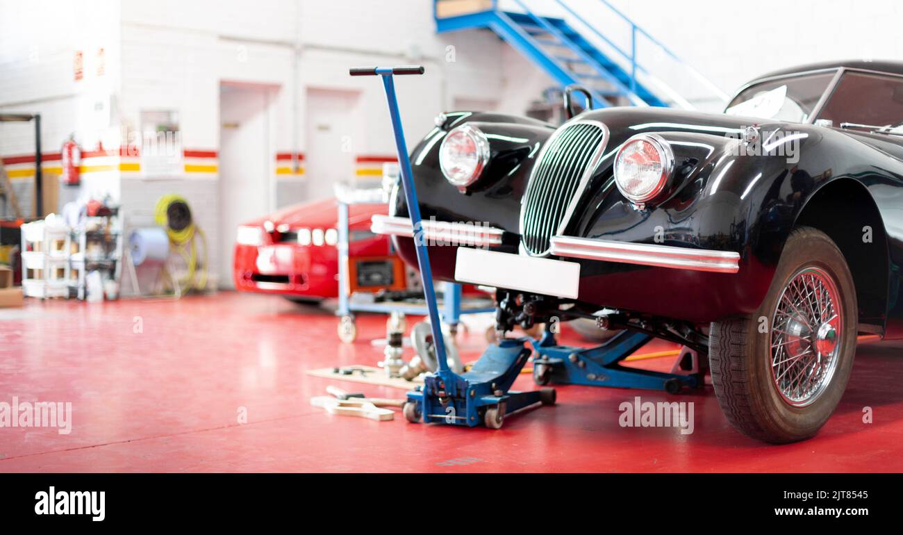 Panoramablick auf das Innere einer Garage. Oldtimer wird repariert. Platz für Text. Stockfoto