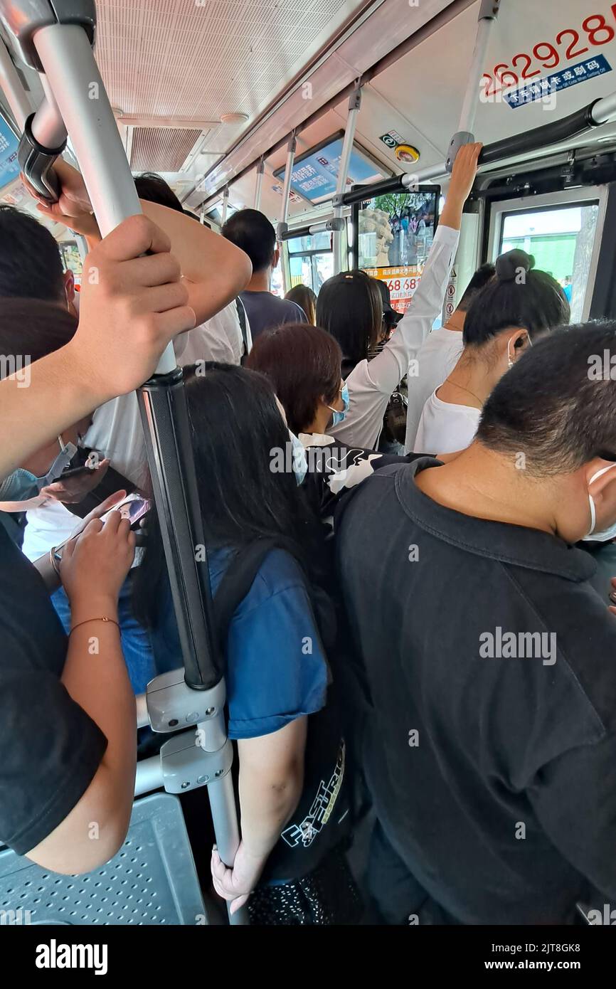 Eine vertikale Aufnahme von Menschen mit Masken in einem überfüllten Bus bei der Coronavirus-Pandemie in Peking, China Stockfoto