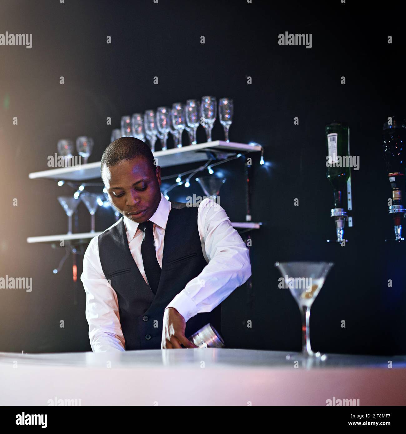 Ich serviere nur das Beste. Ein gut gekleideter Barkeeper, der hinter dem Tresen steht. Stockfoto