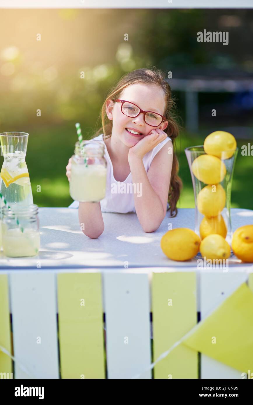 Es ist frisch gepresst. Porträt eines kleinen Mädchens, das Limonade von ihrem Stand draußen verkauft. Stockfoto
