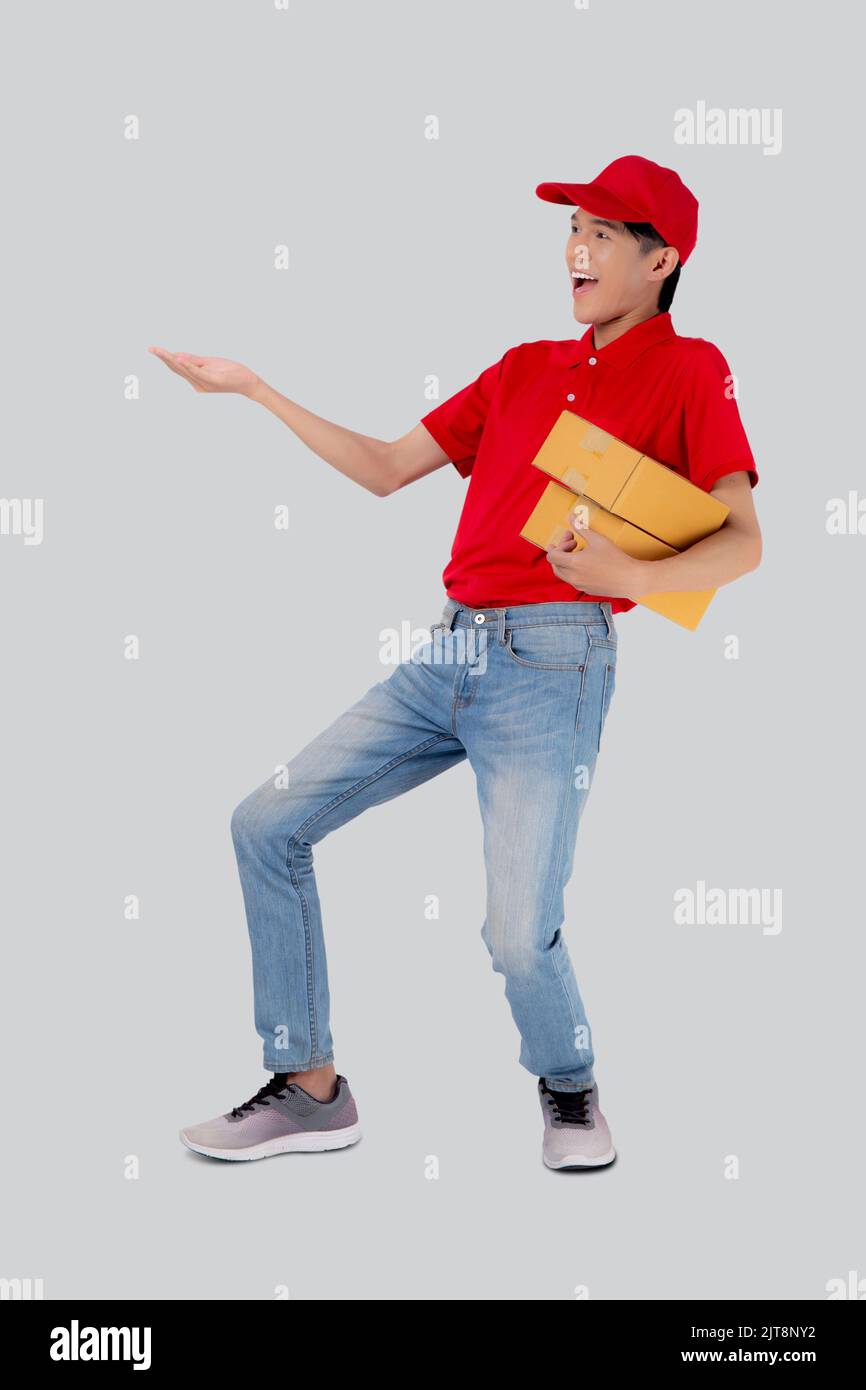 Junger asiatischer Mann in Uniform rot und Kappe stehend Tragebox Stapel isoliert weißen Hintergrund, Mitarbeiter hält Fracht oder Paket, Kurier und Lieferung, Stockfoto