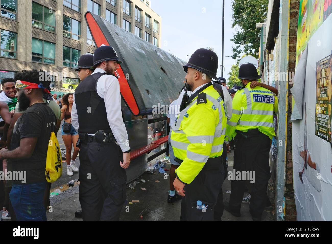 London, Großbritannien, 28.. August 2022. Eine Busstation bricht zusammen, nachdem das Gewicht von einem halben Dutzend Nachtschwärmer sie zum Nachgeben veranlasste. Der Notting Hill Carnival kehrt nach einer dreijährigen Pause nach London zurück, die durch die Covid-Pandemie mit Children's Day - oder Family Day - verursacht wurde. Schätzungsweise zwei Millionen Besucher werden das Gebiet während des Feiertagswochenendes besuchen. Neben den lebhaften Paraden, die stattfinden, sind Bühnen, Soundsysteme, karibische Imbissstände und Getränkestände entlang der Route verteilt. Kredit: Elfte Stunde Fotografie/Alamy Live Nachrichten Stockfoto