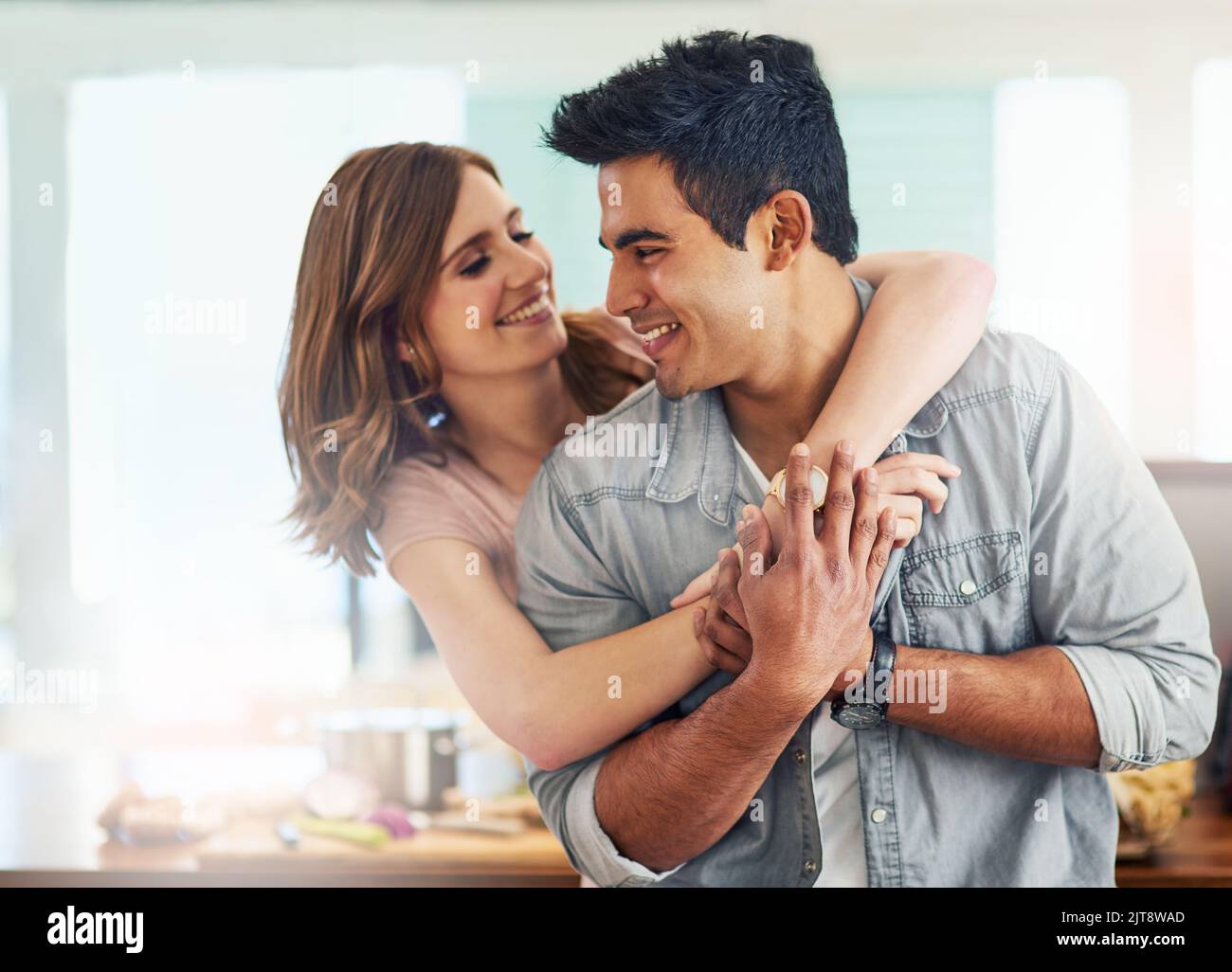 Ich kann gar nicht genug von Euch bekommen. Ein liebevolles junges Paar, das in der Küche steht. Stockfoto