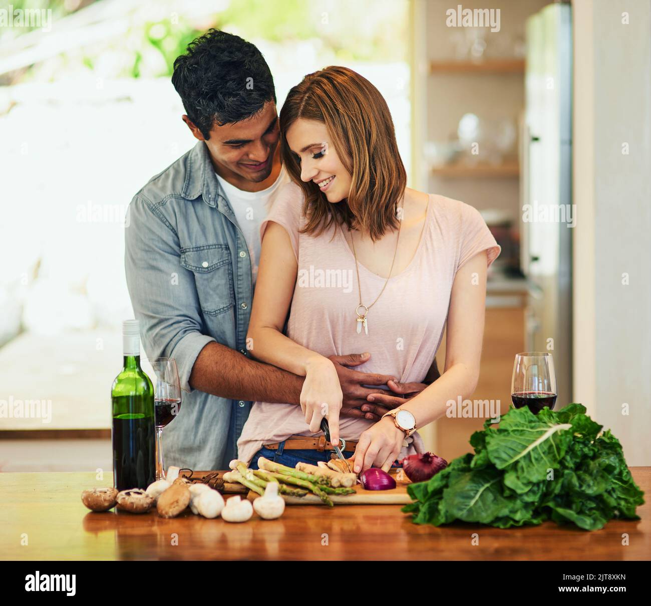 Ein junger Mann umarmte seine Frau, während sie das Abendessen zubereitete. Stockfoto