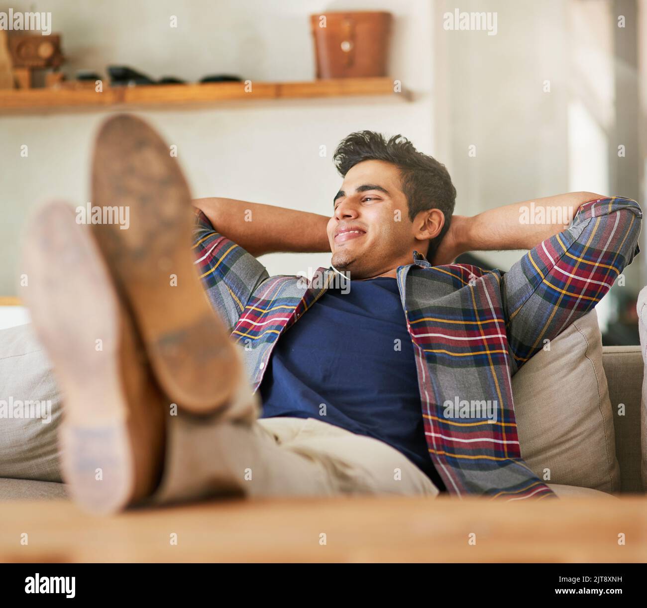 Komfort zu Hause. Ein hübscher junger Mann, der sich zu Hause auf dem Sofa entspannt. Stockfoto