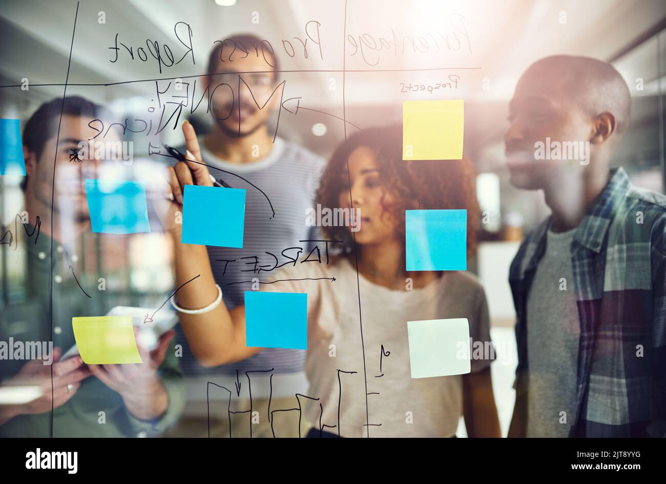 Eine erfolgreiche Strategie. Eine Gruppe junger Designer plant auf einer Glasplatte. Stockfoto