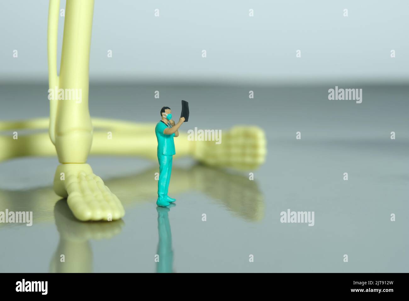 Miniatur Menschen Spielzeug Figur Fotografie. Eine Krankenschwester, die auf das Röntgenergebnis schaut, scannt einen Film vor dem Beinknochenskelett. Bildfoto Stockfoto