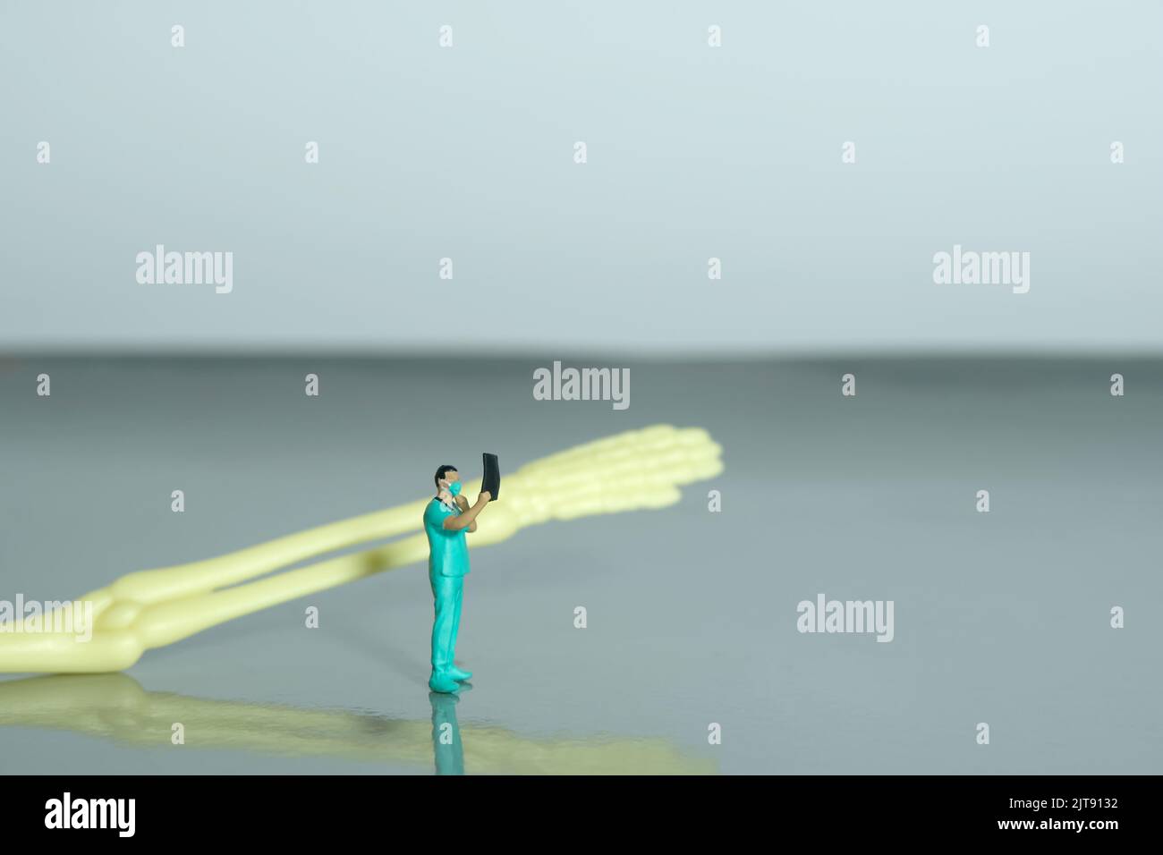 Miniatur Menschen Spielzeug Figur Fotografie. Eine Krankenschwester, die auf das Röntgenergebnis schaut, scannt einen Film vor dem Handknochenskelett. Bildfoto Stockfoto