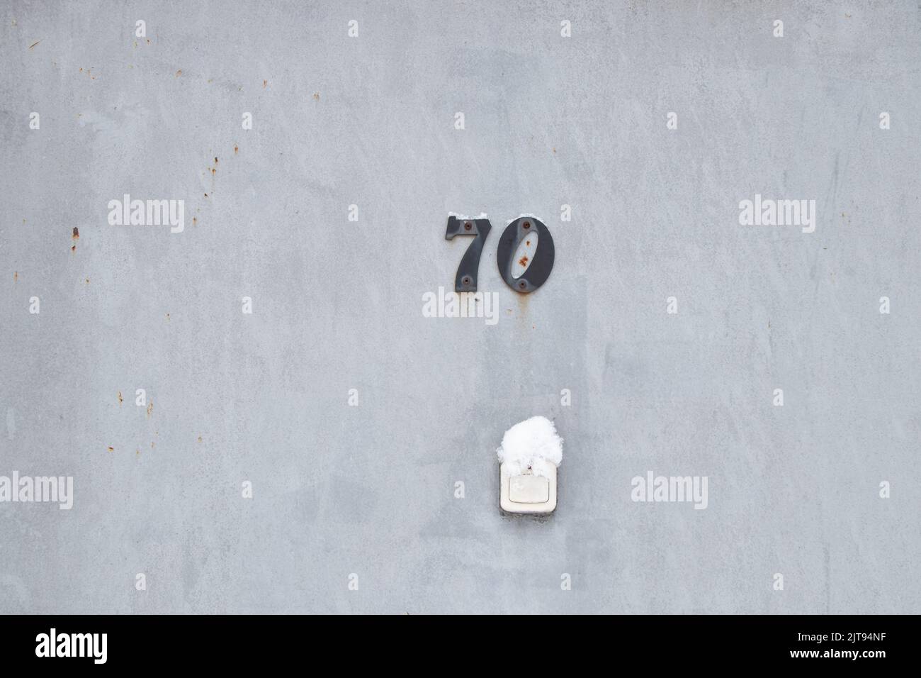 Haus Nummer 70 an der eisernen Tür der Wohnung und eine Glocke auf der Straße im Schnee im Winter in der Ukraine, Wohnung 70, Hausnummer Stockfoto