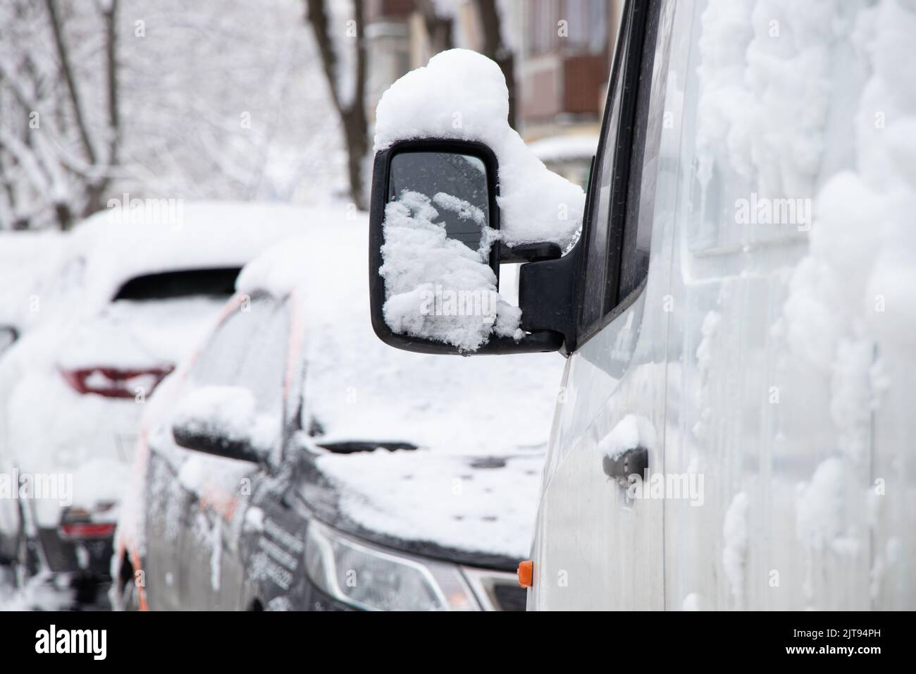 Geparkte Autos am Straßenrand entlang der Häuser am Morgen auf der Straße in der Stadt im Schnee, die Stadt Dnipro in der Ukraine, Winterwetter in Th Stockfoto