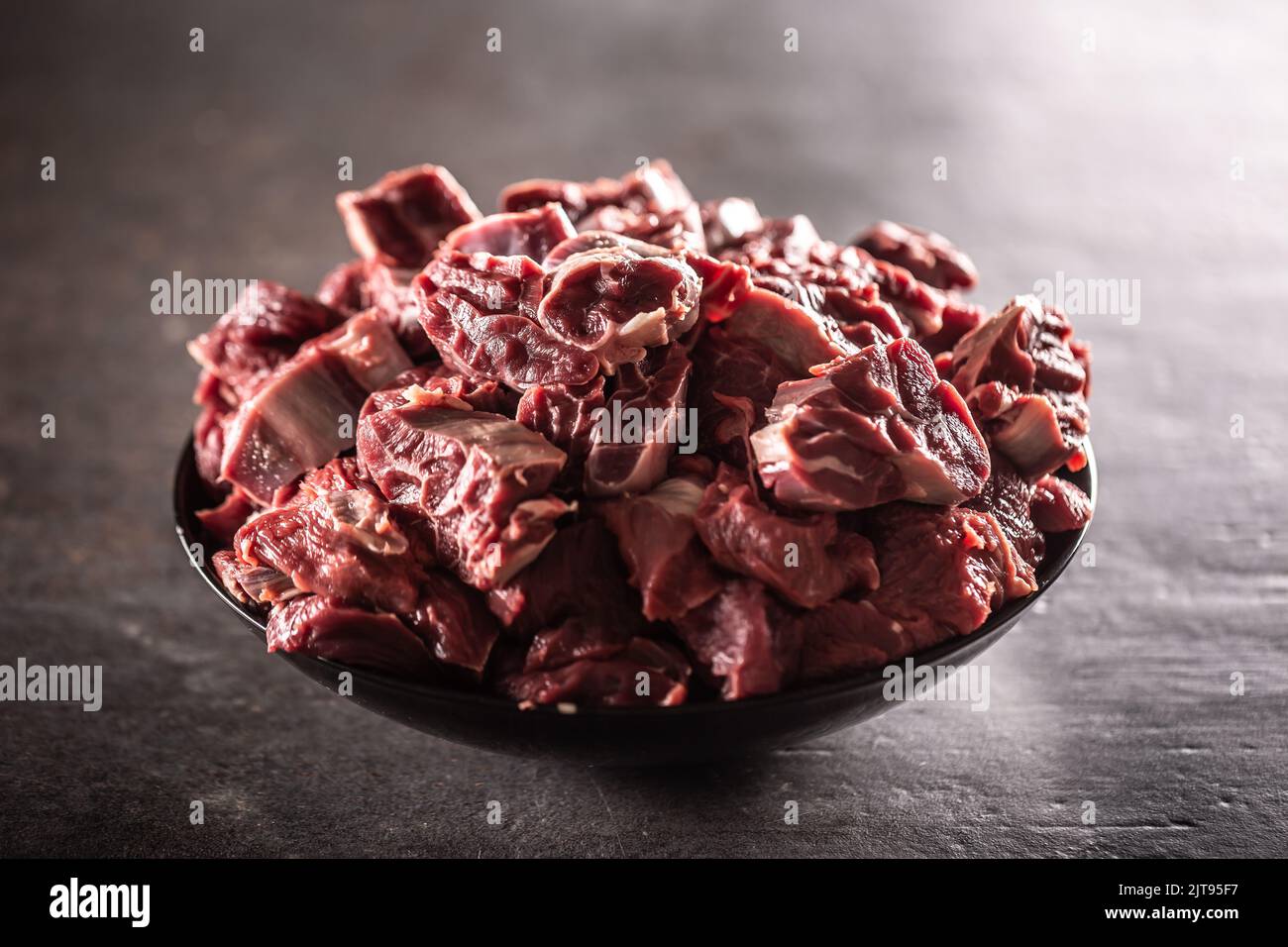 Schüssel voll mit kleinen Fleischstücken auf einer schwarzen metallischen Oberfläche. Stockfoto