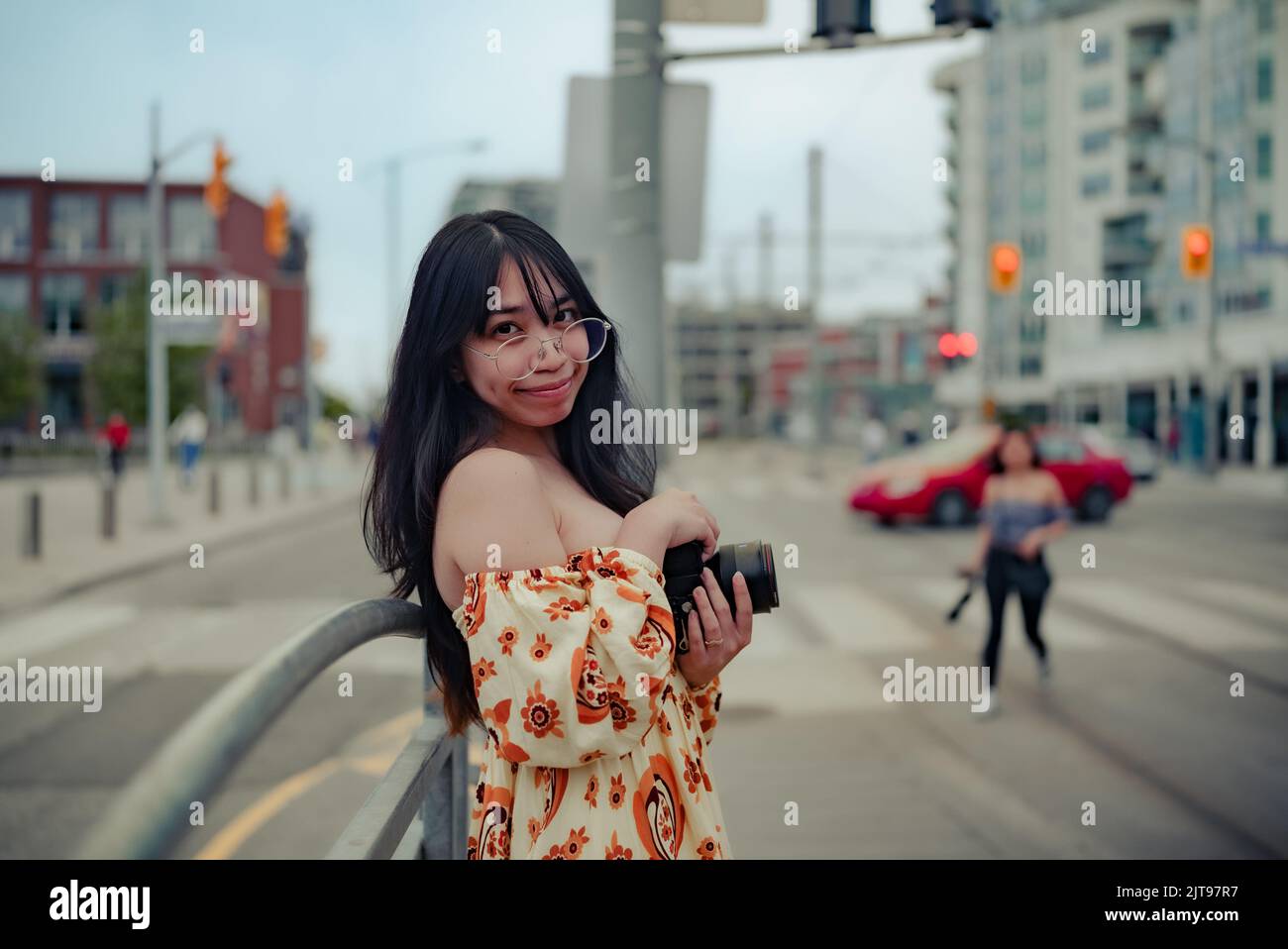 Eine asiatische Frau, die in einem Kleid die Kamera hält und die Kamera in der Straße von Toronto anschaut Stockfoto