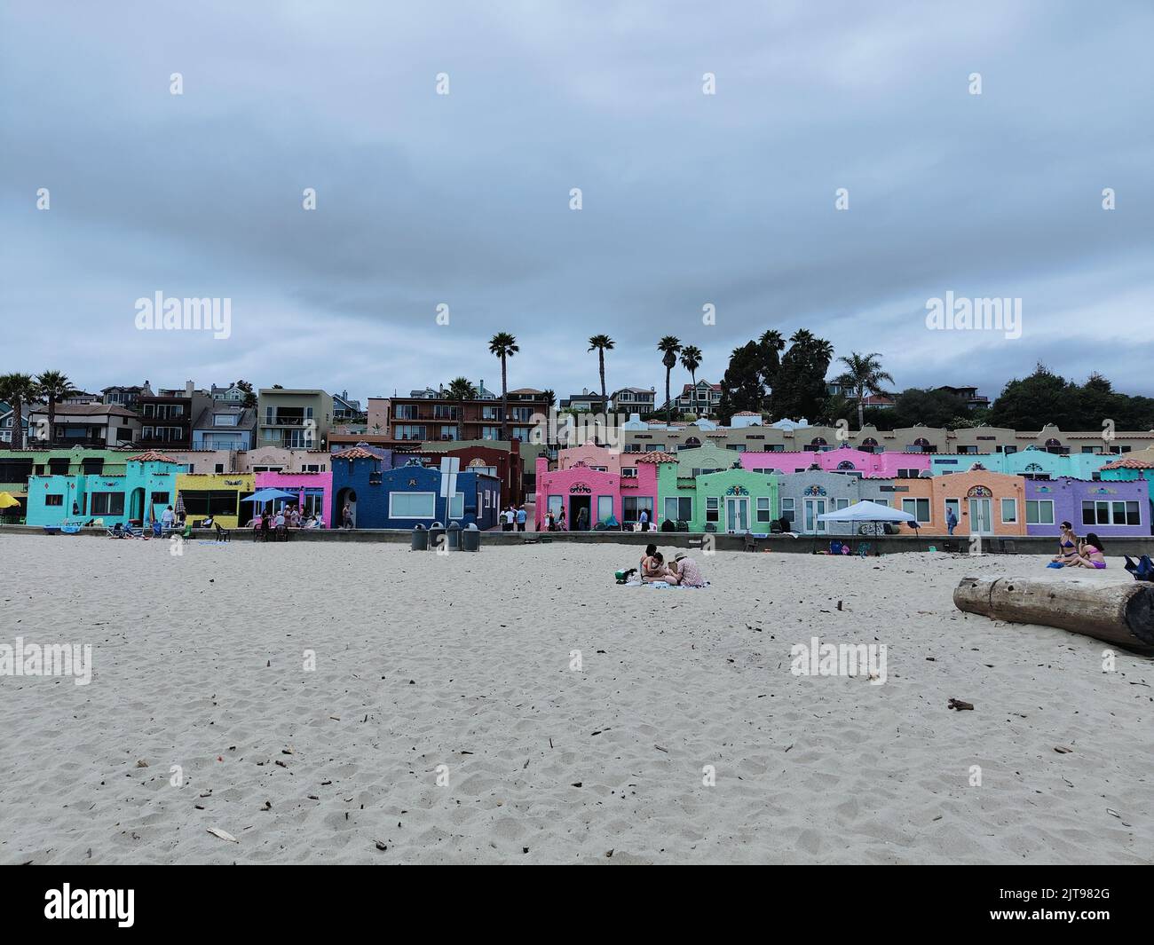 Ein Blick auf den Capitola-Strand mit bunten Häusern, Bäumen und einigen Leuten, die im Sand sitzen, Kalifornien Stockfoto