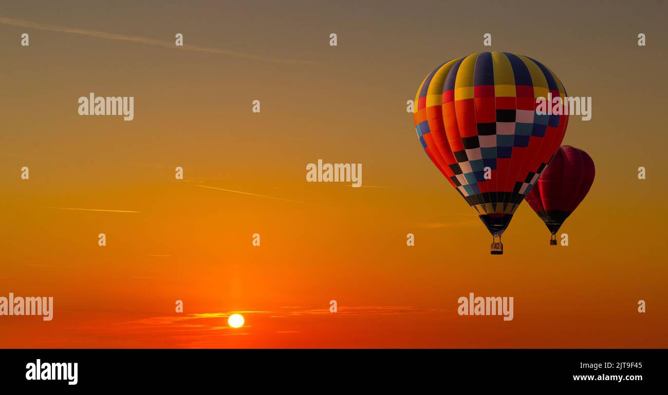 Bunte Heißluftballons fliegen auf dem Sonnenuntergang Himmel Hintergrund. Stockfoto