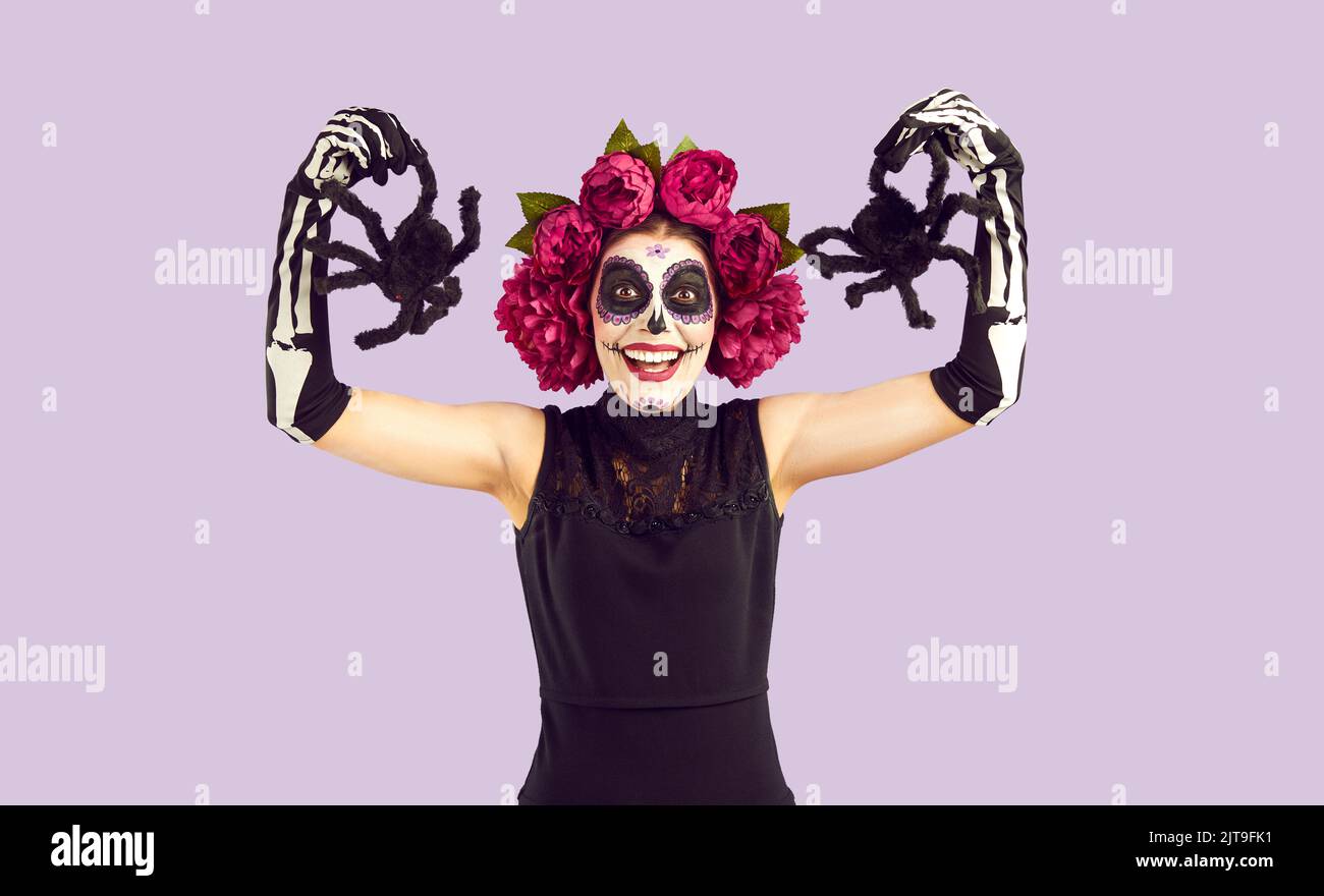 Fröhliche Frau mit mexikanischem traditionellem Make-up für den Tag der Toten, die mit dekorativen Spinnen posiert. Stockfoto