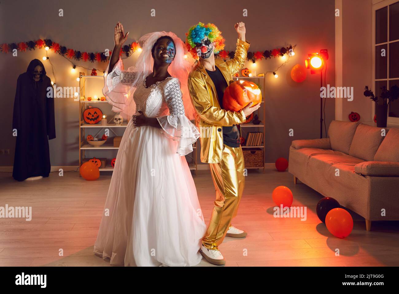 Zwei glückliche Freunde in Dead Bride und Clown Outfits gekleidet, die auf der Halloween Party Spaß haben Stockfoto