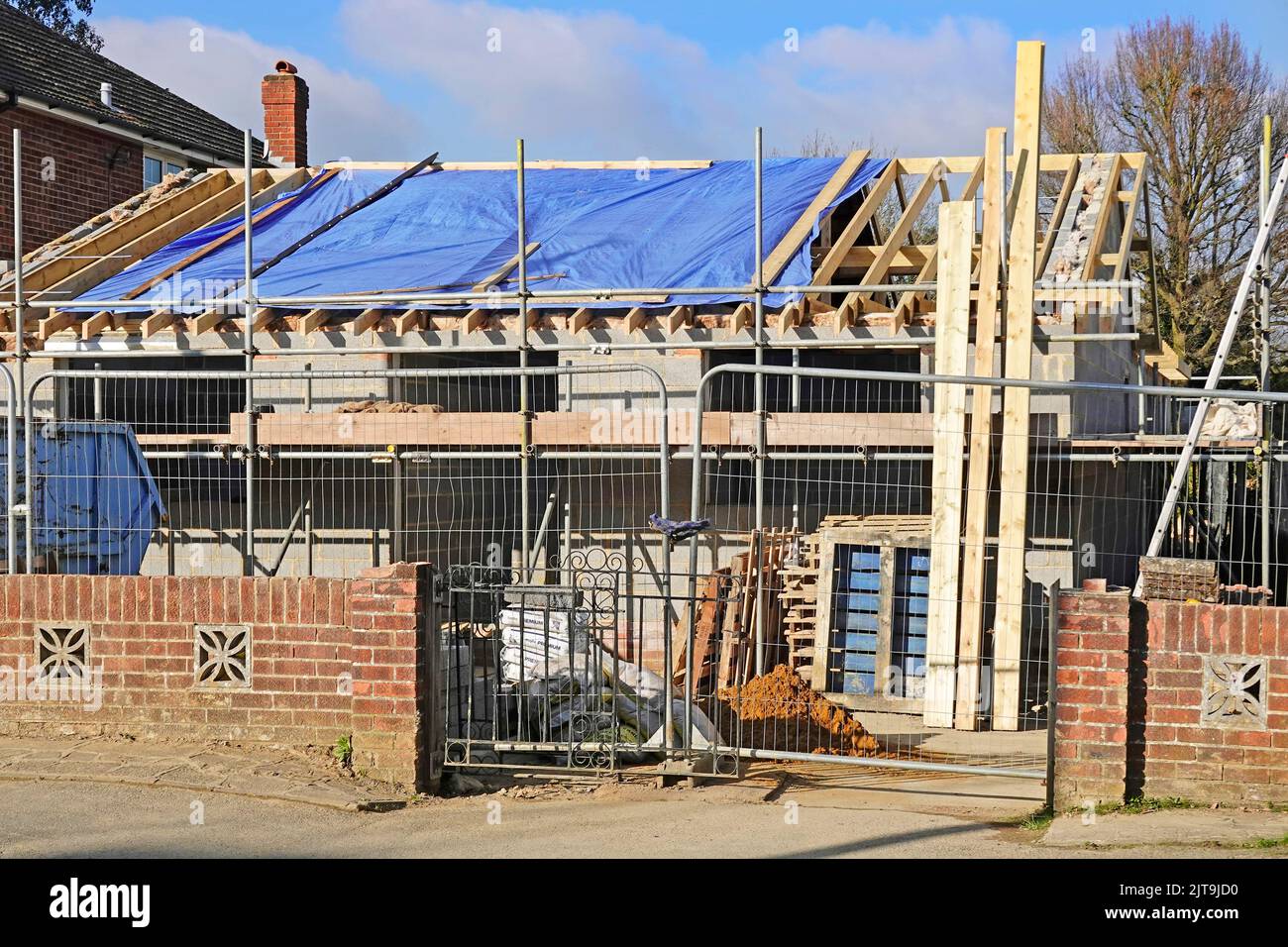 Kompakte Füllung Gehäuse Bungalow Gebäude Baustelle beibehalten vorderen Backstein Grenzwand arbeiten auf Dachhölzern & Gerüst England Großbritannien Stockfoto