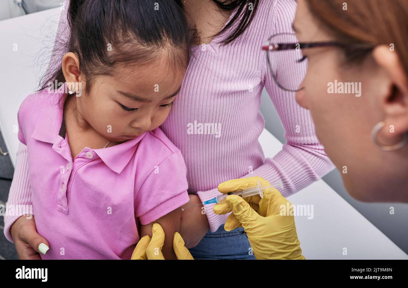 Routineimpfungen für Kinder. Asiatisches Mädchen und ihre Mutter, während sie von einem Hausarzt in einer medizinischen Klinik geimpft wurden Stockfoto