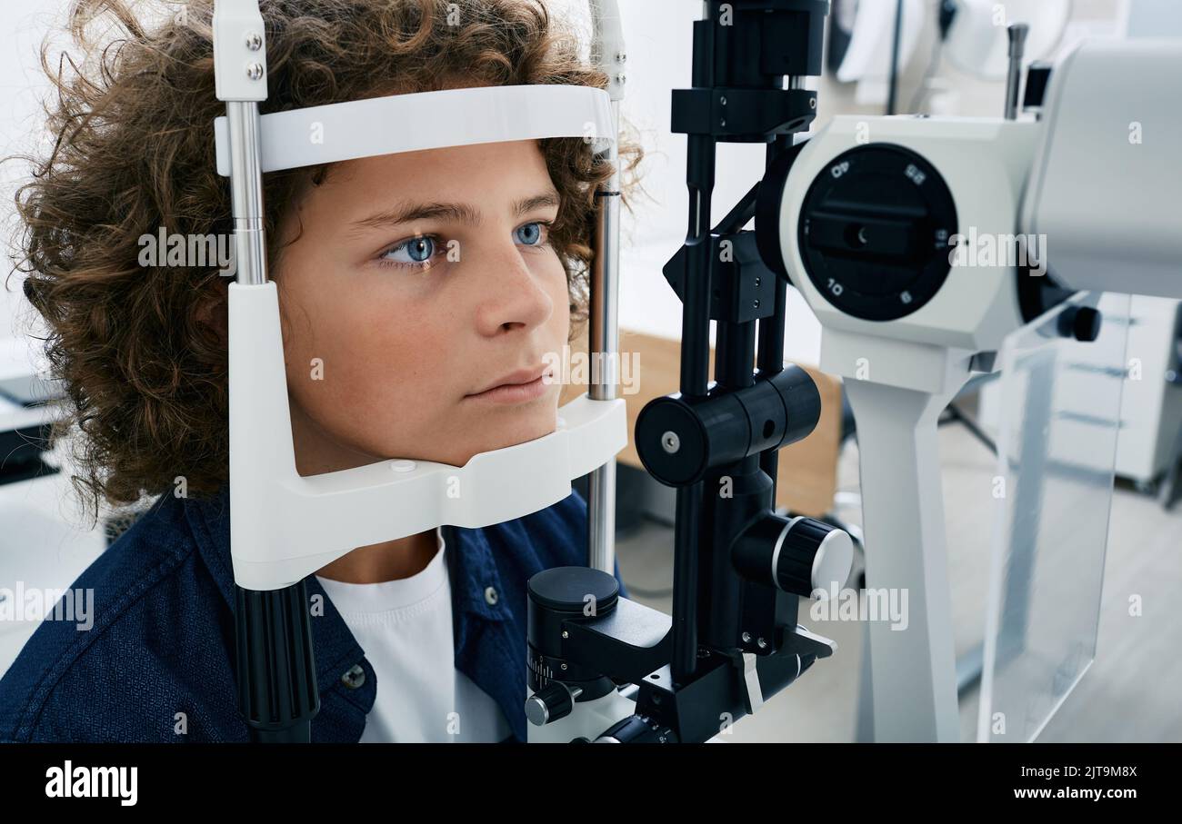 Überprüfung des Sehvermögens des Jungen mit binokularer Spaltlampe, Nahaufnahme. Sehkorrektur bei Kindern Stockfoto