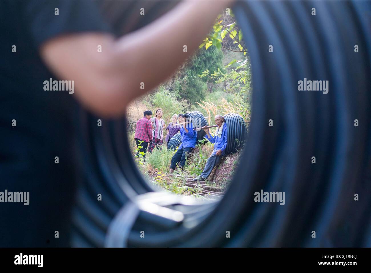 CHONGQING, CHINA - 29. AUGUST 2022 - Dorfbewohner tragen Wasserleitungen auf einen Berg, um Quellwasser auf einen Berg abzuleiten, um Trinkwasser in Chong zu speichern Stockfoto
