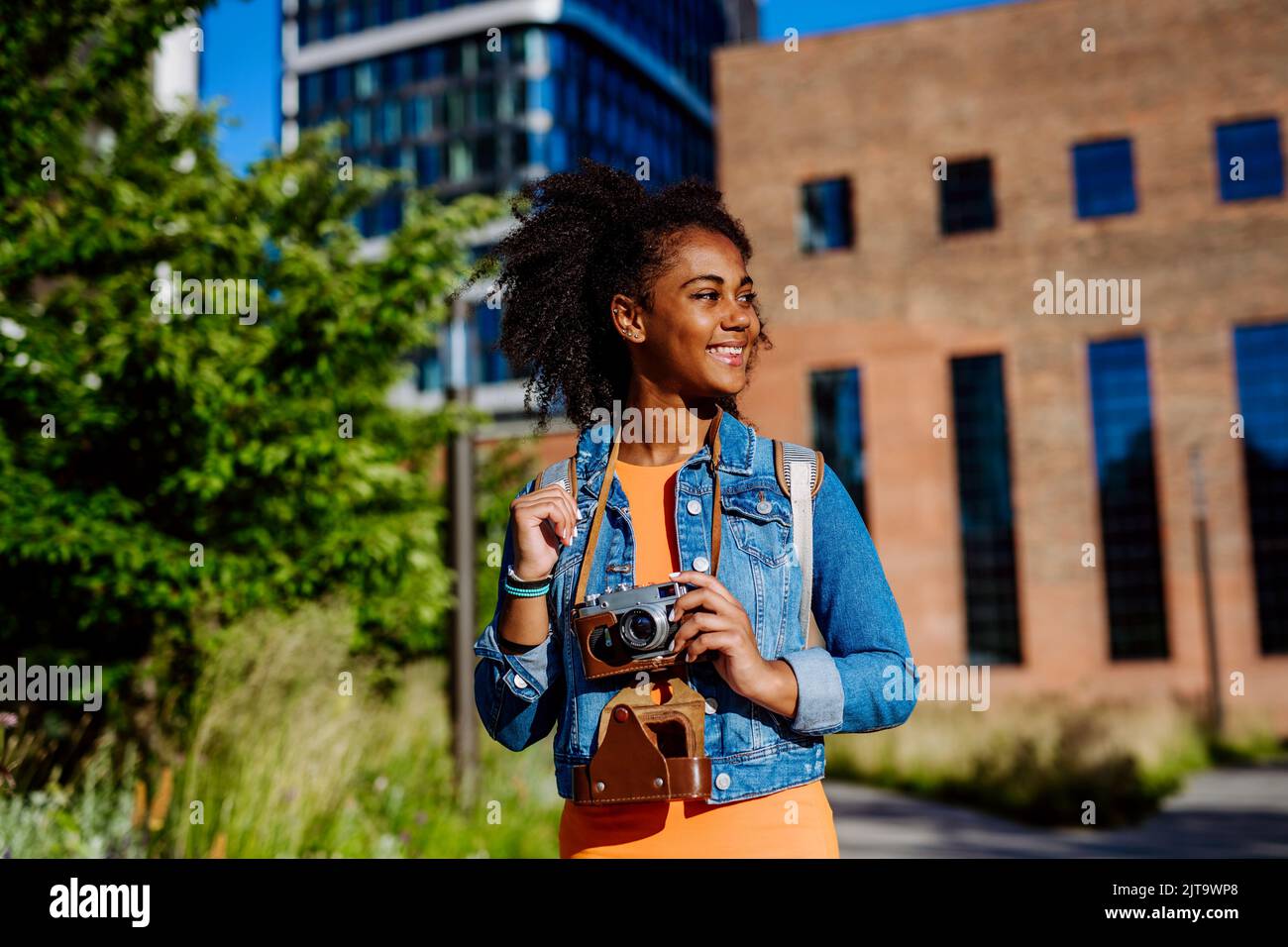 Multirassisches Mädchen, das mit der Kamera in der Stadt läuft und Fotos macht. Stockfoto